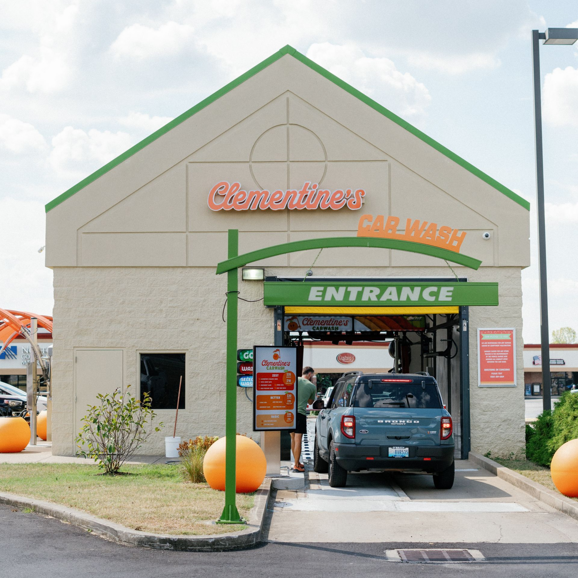 A cartoon orange holding a flag that says car wash