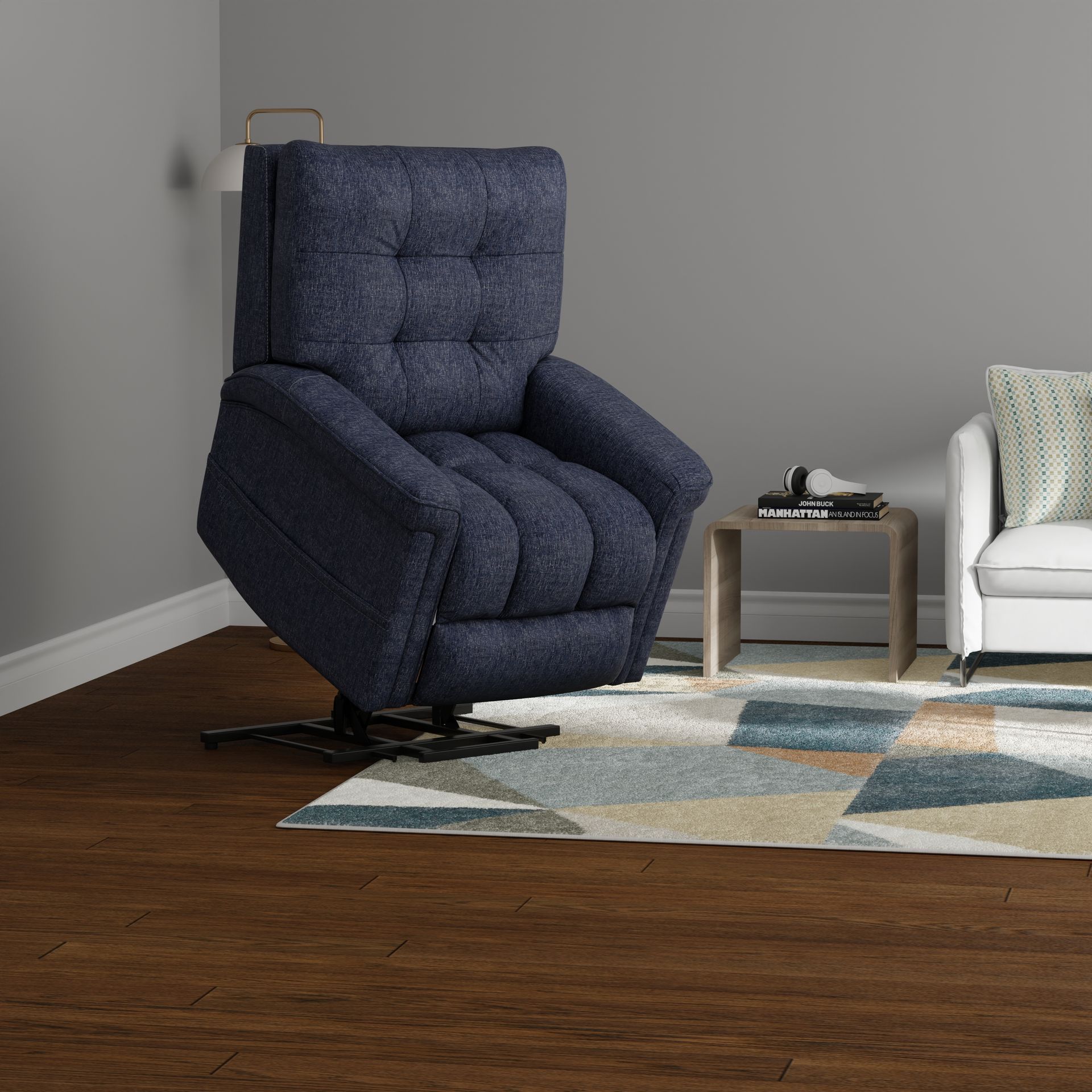 A navy blue tufted recliner in a room with hardwood floors, a geometric area rug, a side table, and a white sofa.
