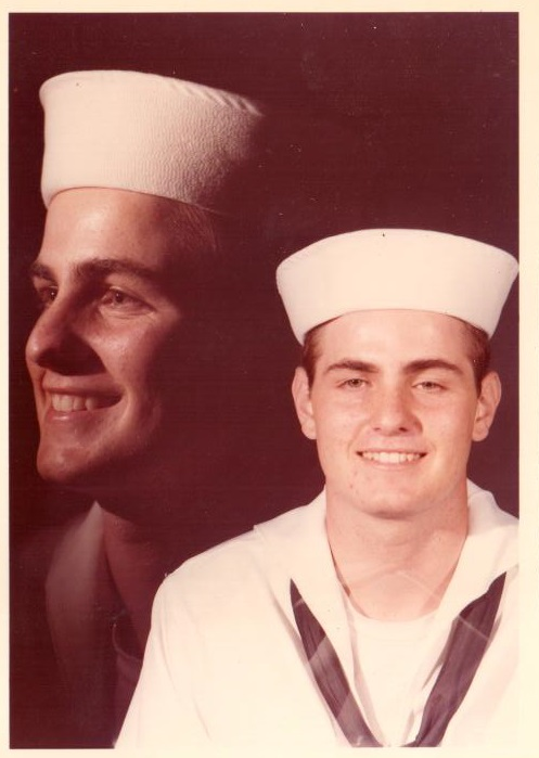 Two men are posing for a picture and one is wearing a white hat