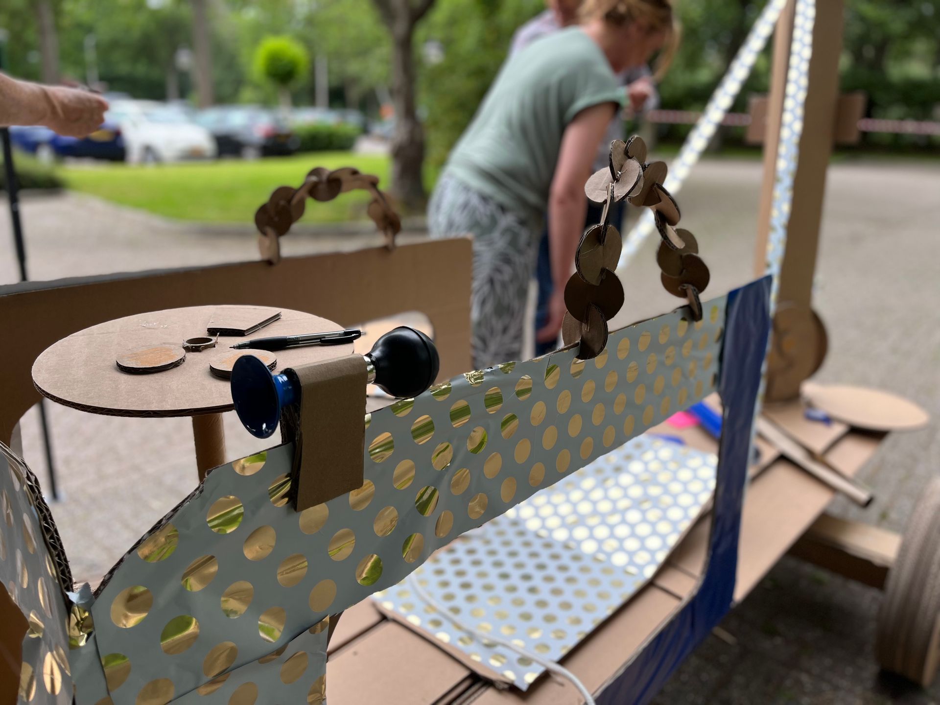 Een vrouw staat achter een kartonnen sculptuur.