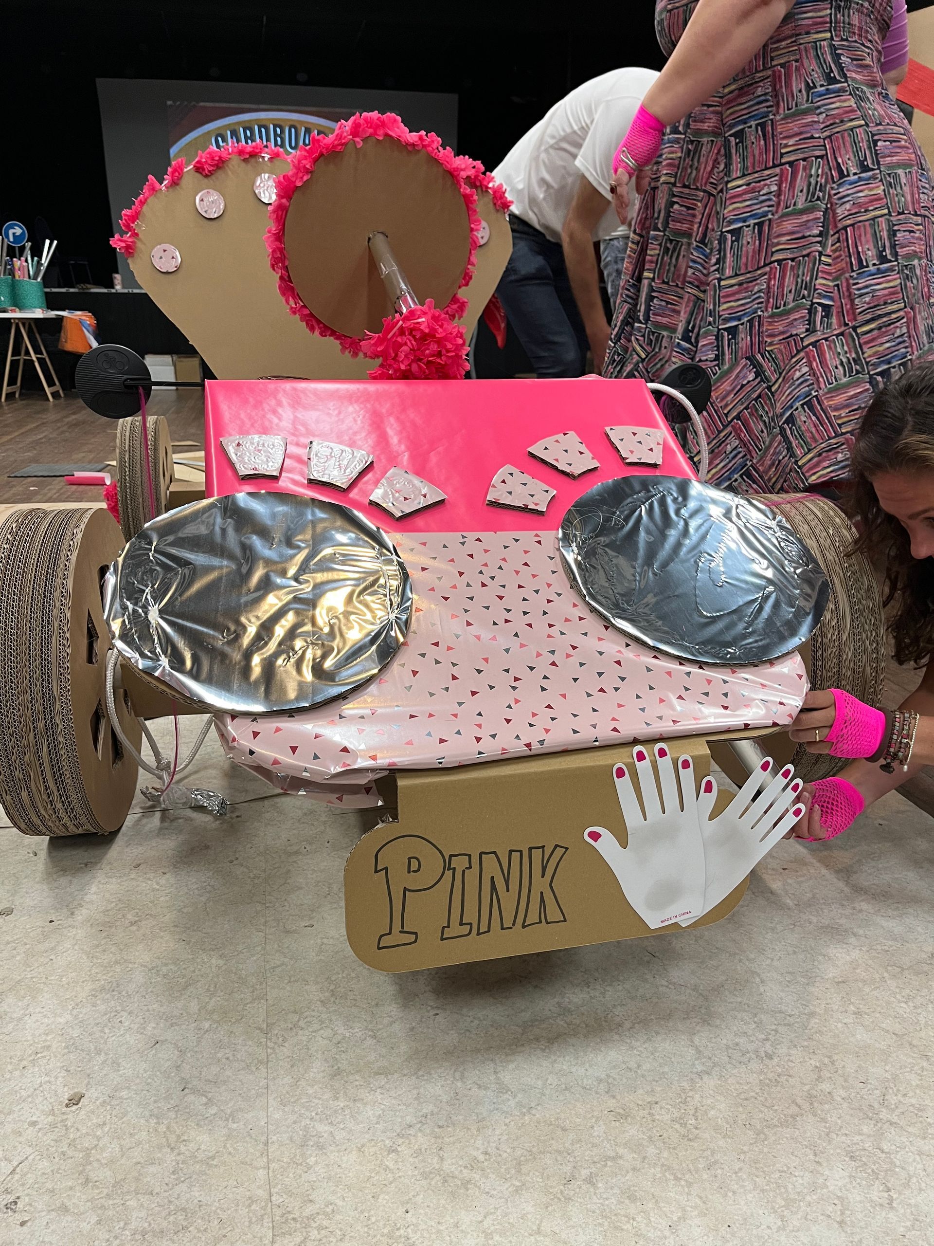 Een kartonnen auto met een bordje waarop roze staat