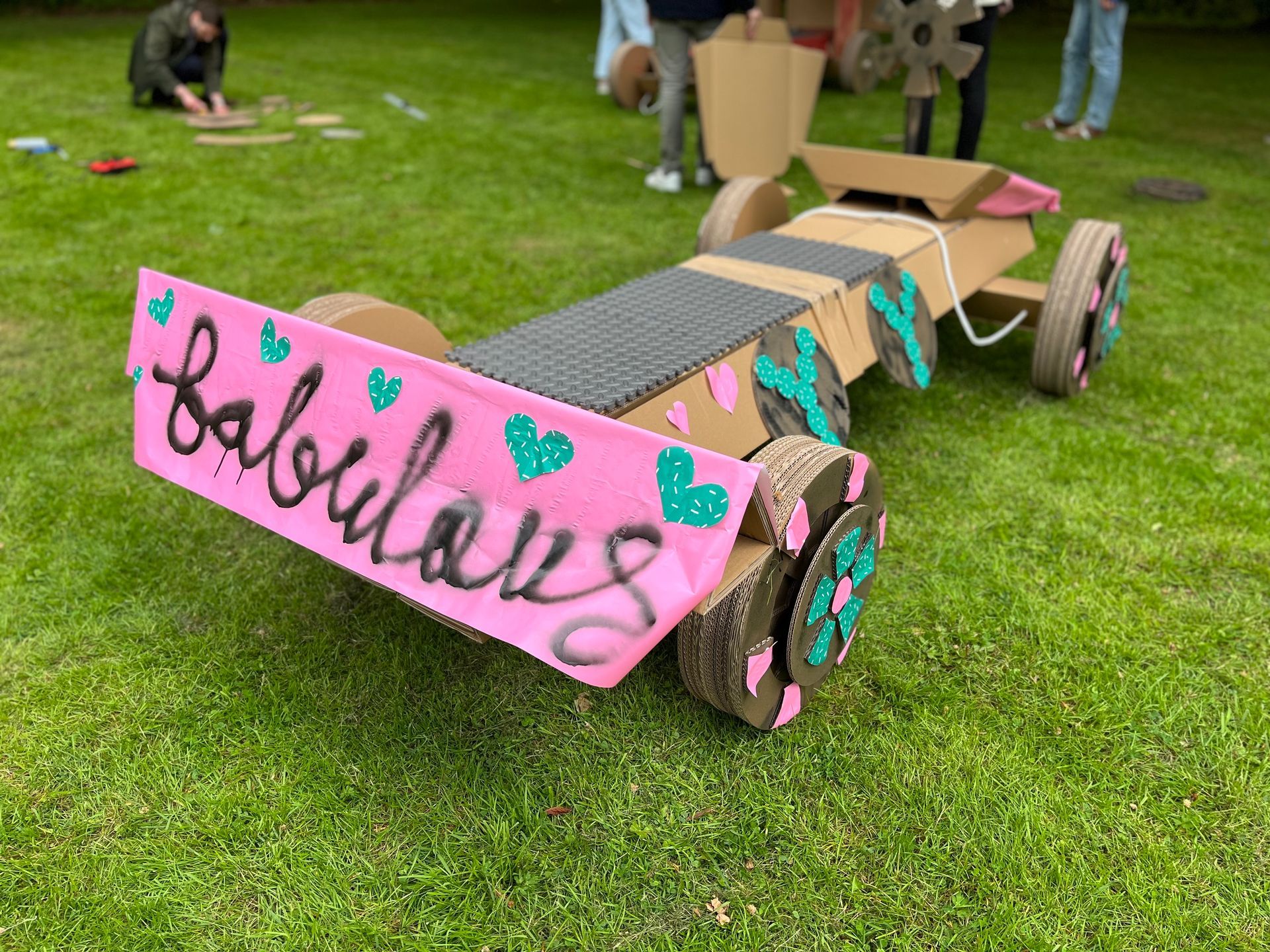 Een kartonnen auto staat bovenop een weelderig groen veld.