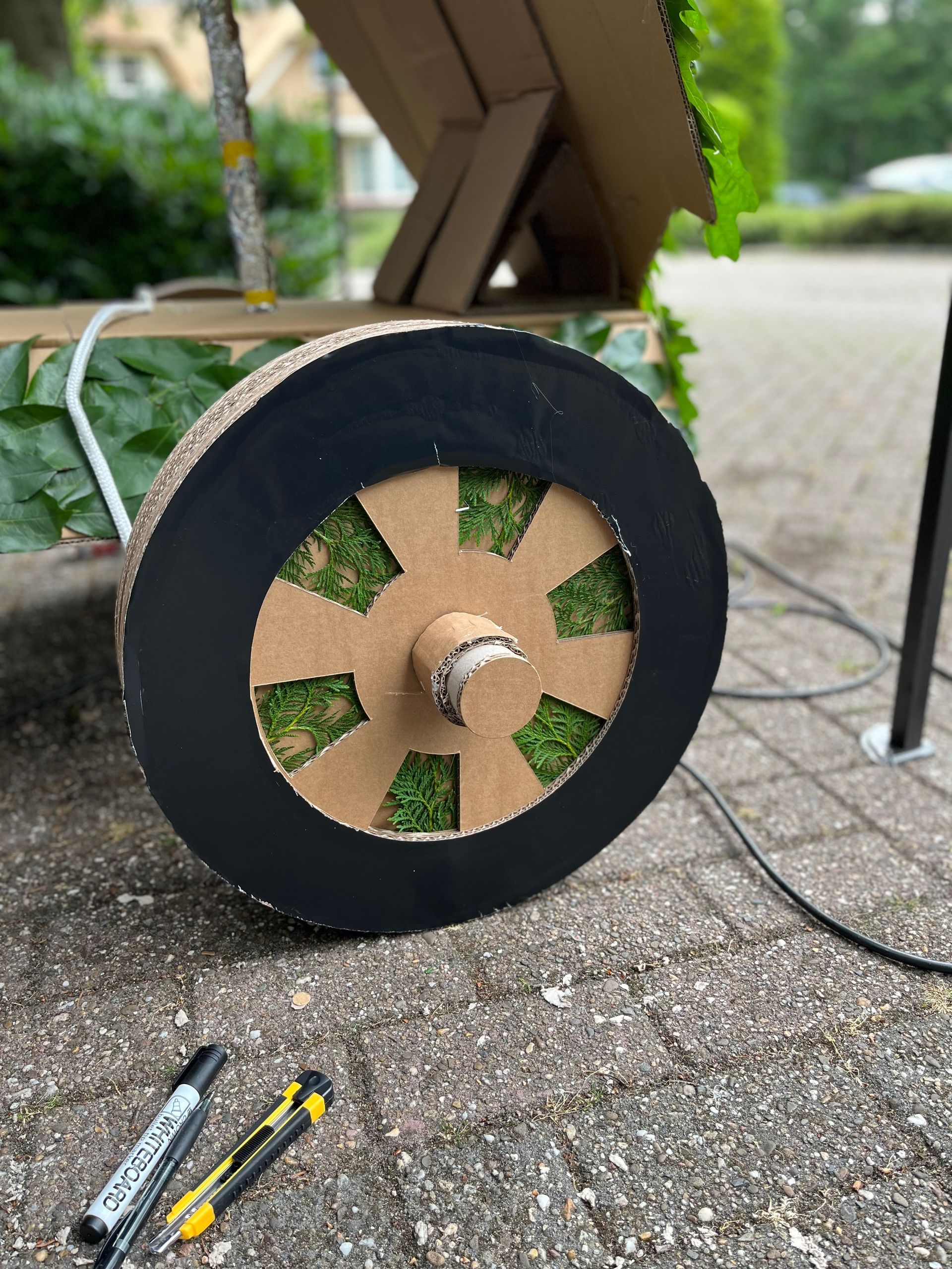 Naast de markeringen ligt een kartonnen wiel met mos erop op de grond.