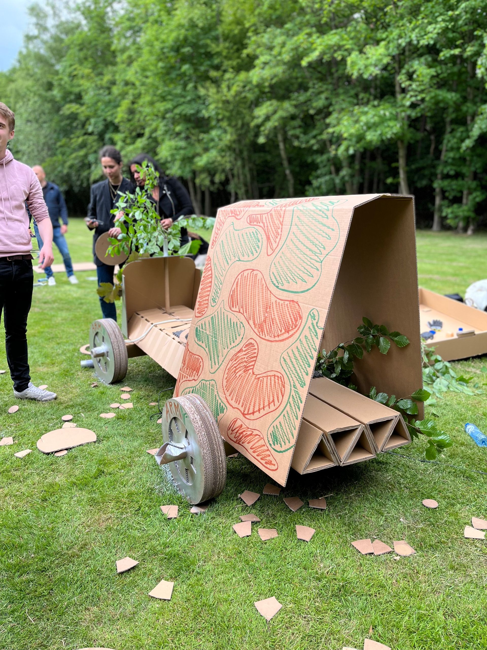 Een kartonnen auto staat bovenop een weelderig groen veld.