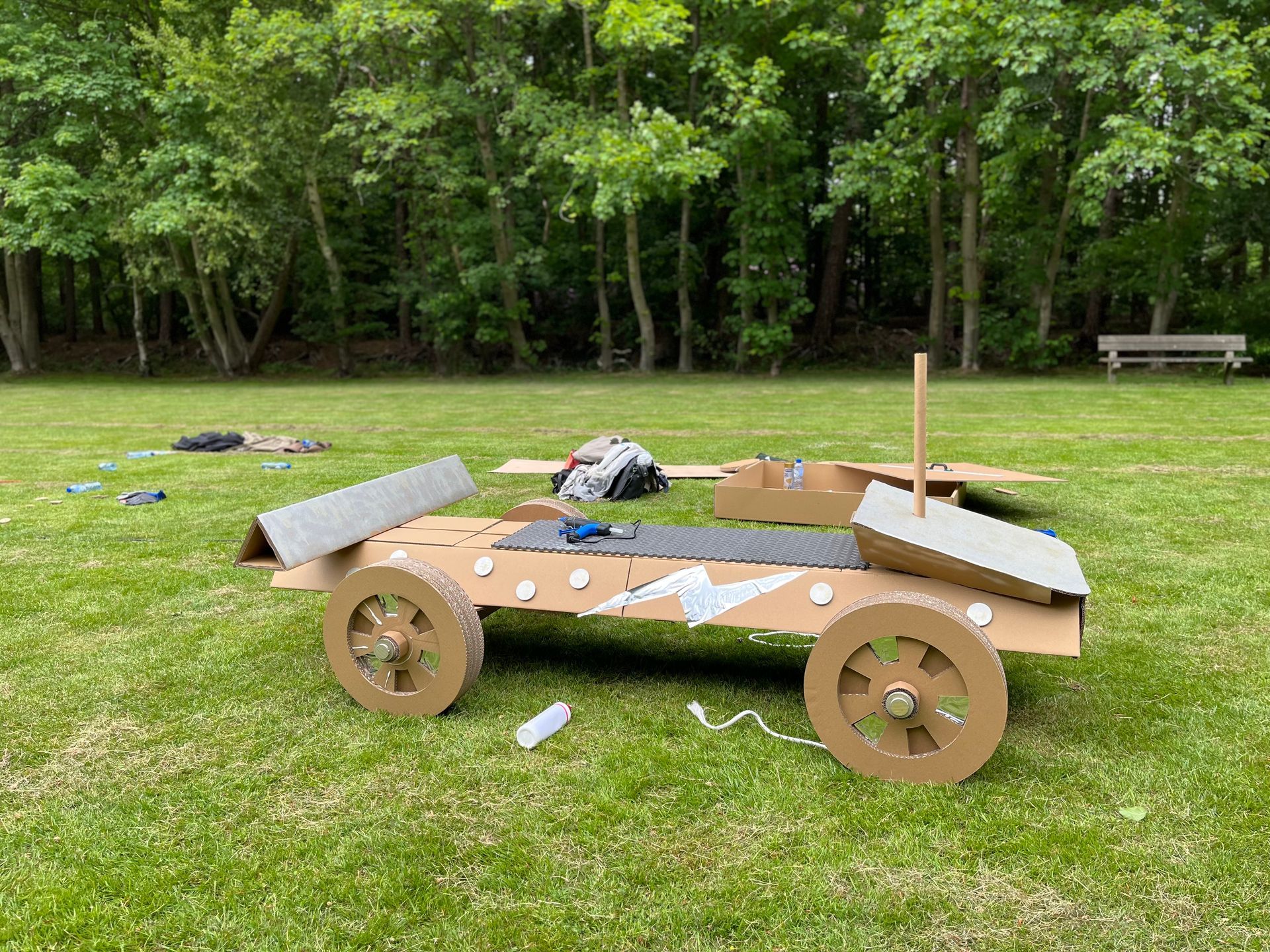 Een kartonnen auto staat bovenop een weelderig groen veld.