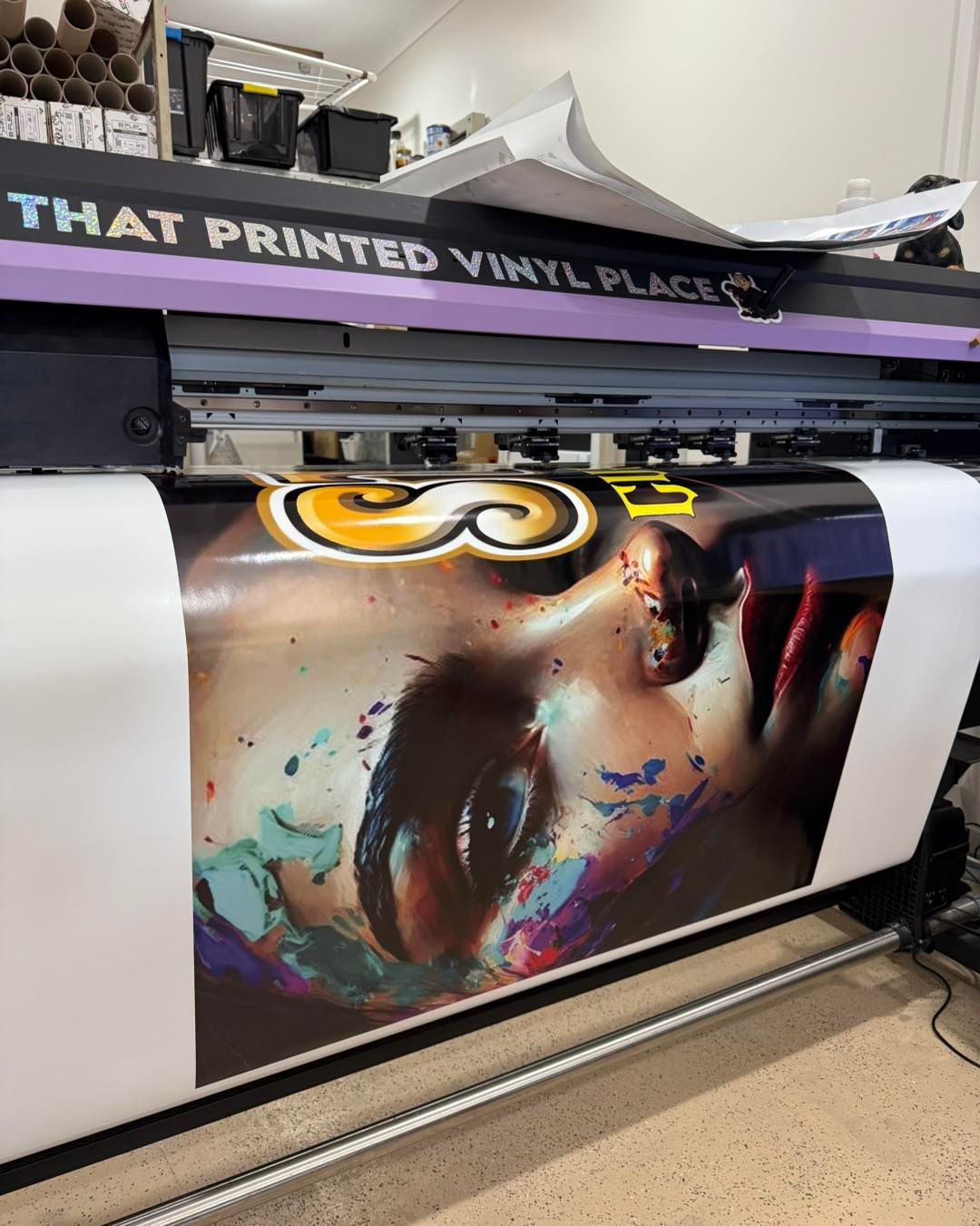 Large format printer printing a colorful portrait onto vinyl. Workplace setting.— That Printed Vinyl Place in Heatley, QLD