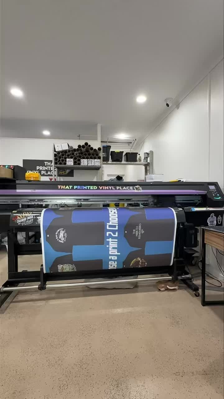 Large format printer printing a banner with blue and black graphics in a print shop — That Printed Vinyl Place in Heatley, QLD