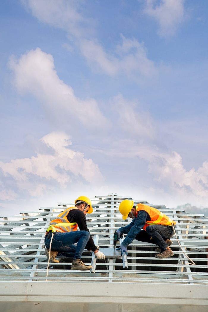 two construction workers are working on the roof of a building