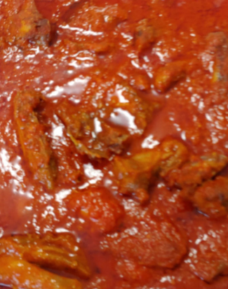 A tin foil container filled with meat and sauce