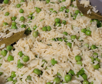 A pan filled with rice and peas on a stove.