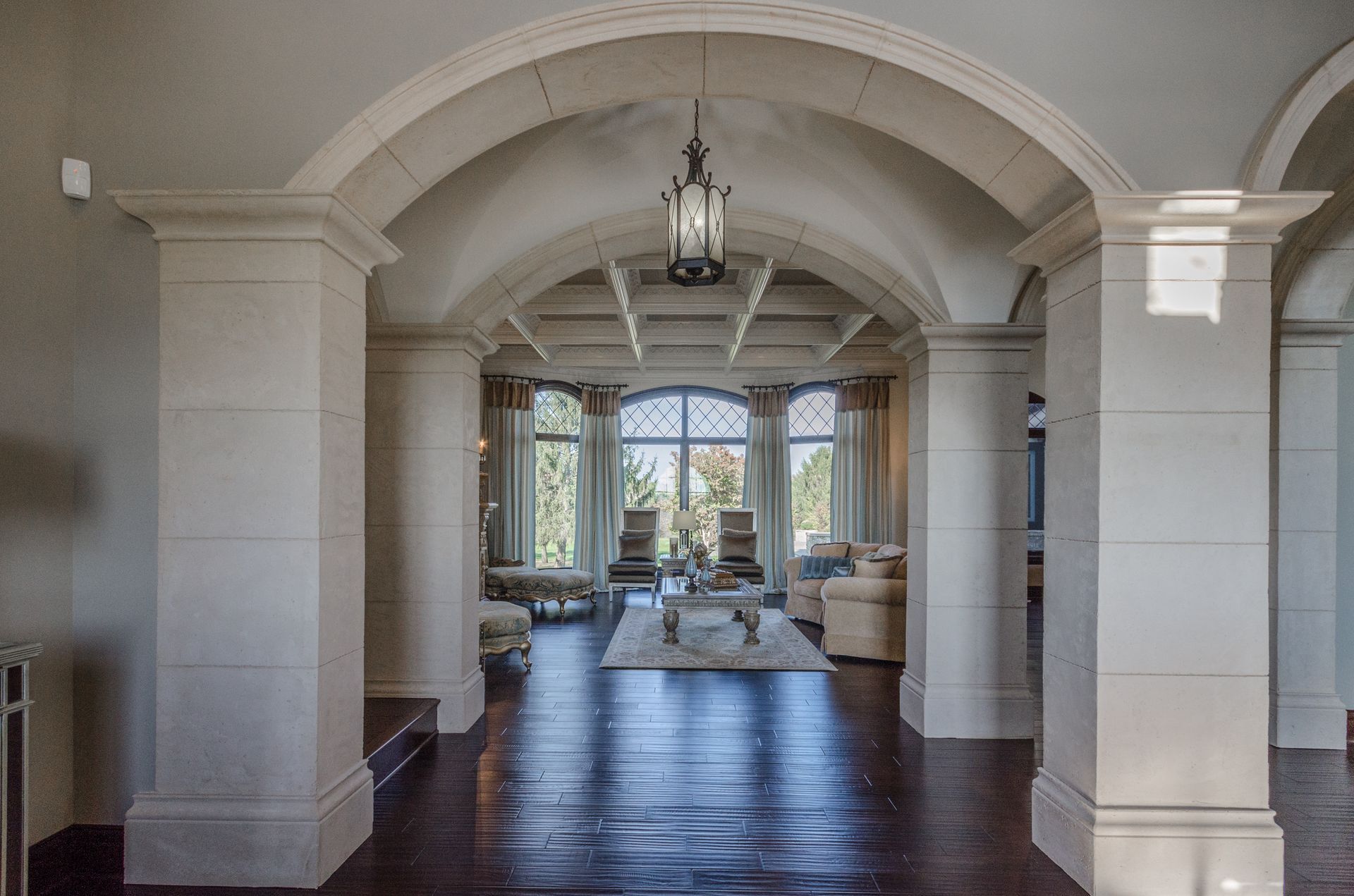 A Hallway With Columns And Arches Leading To A Living Room - Carmel, IN - Goldberg Design Group