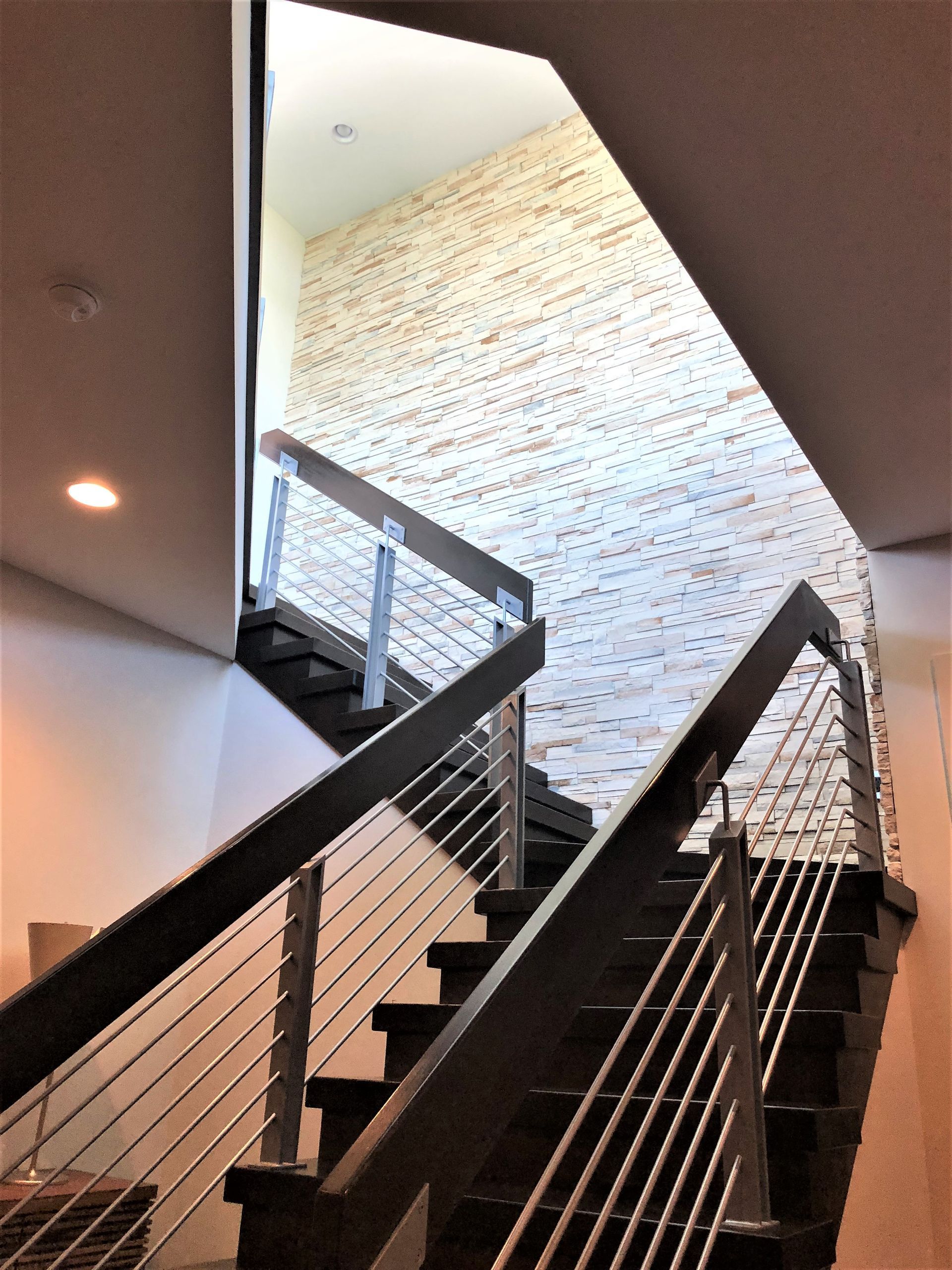 A Staircase With A Stainless Steel Railing And A Brick Wall - Carmel, IN - Goldberg Design Group