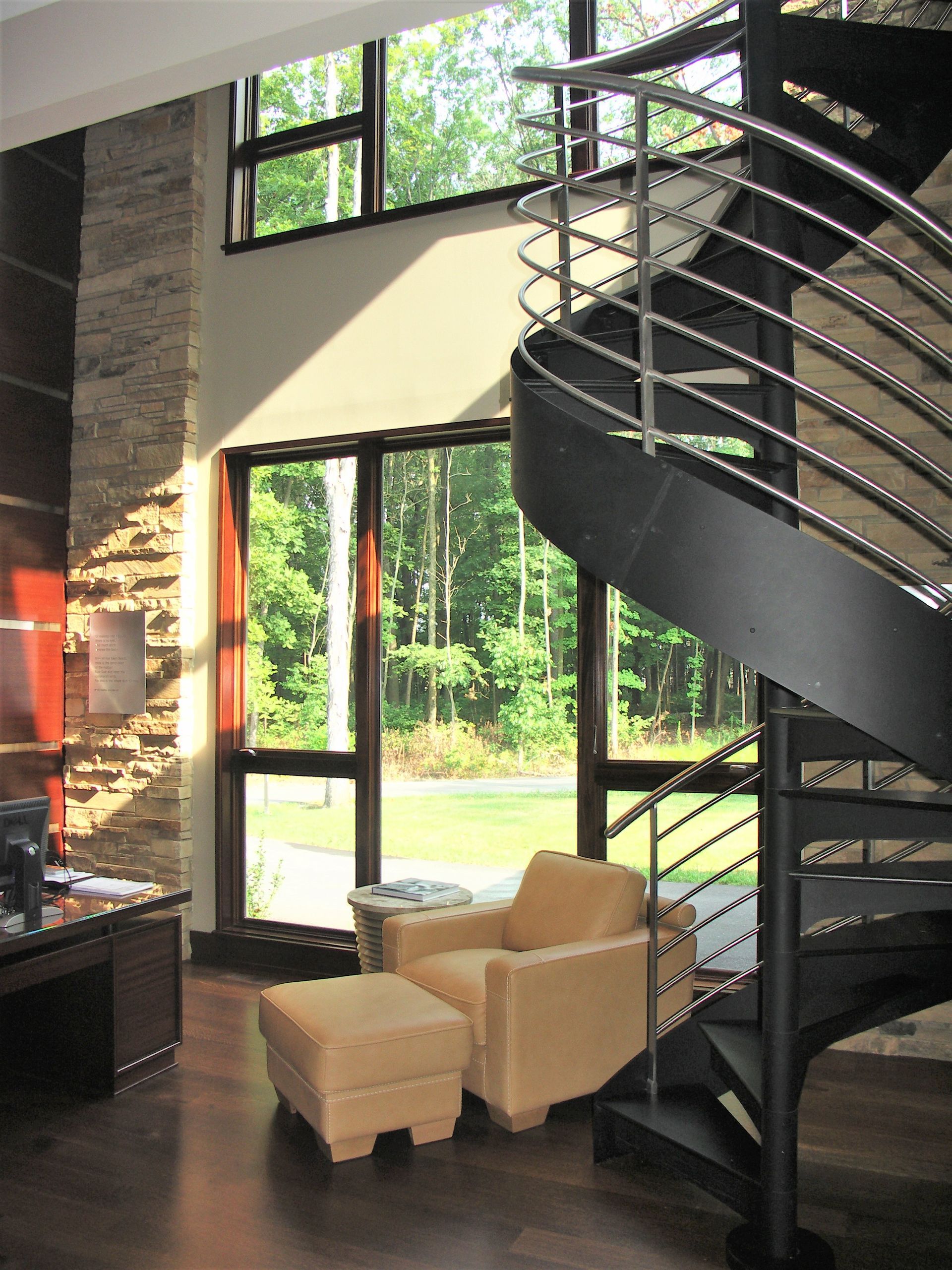 A Living Room With A Spiral Staircase And Chairs - Carmel, IN - Goldberg Design Group