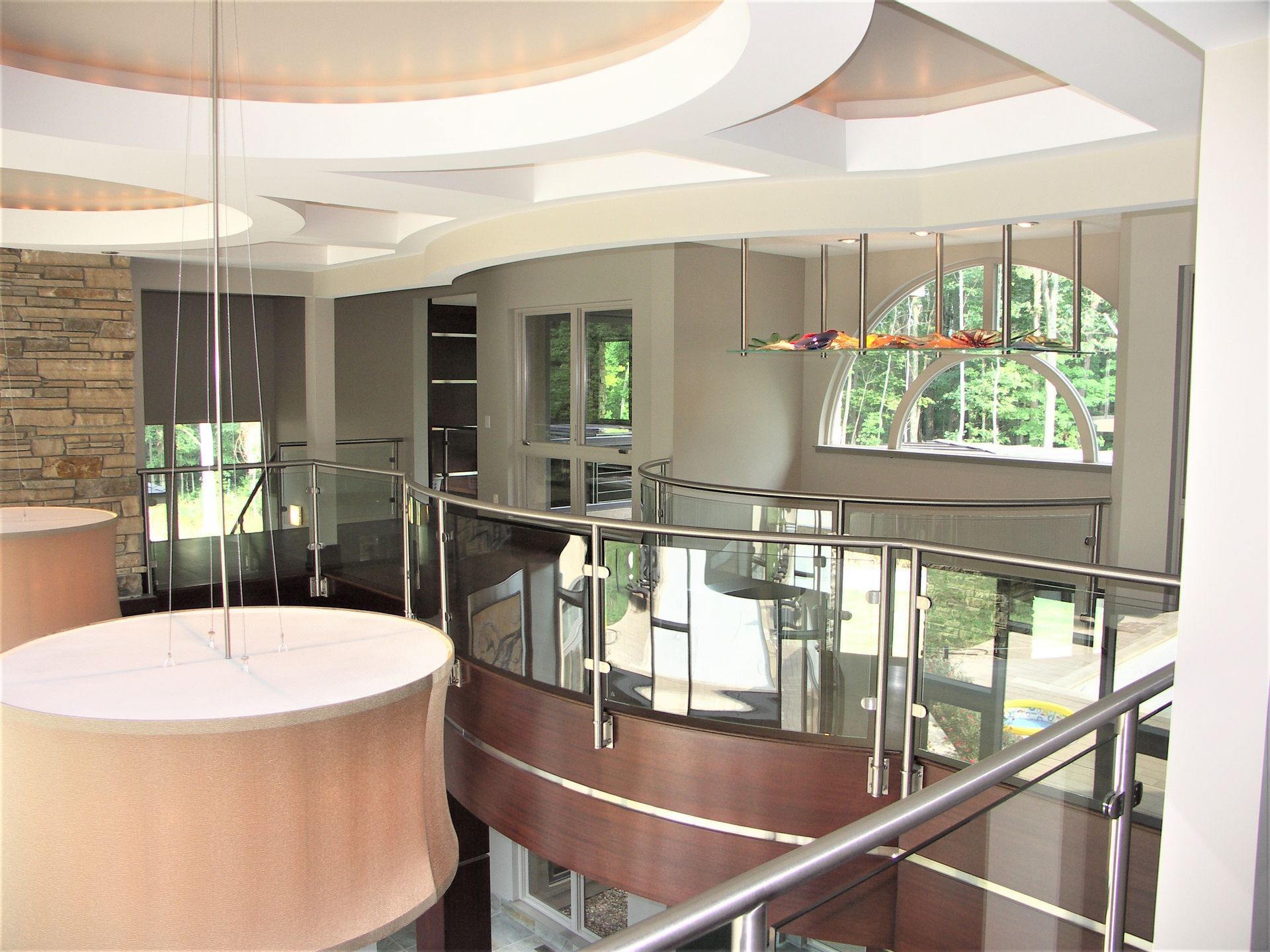 A Large Room With A Curved Staircase And A Glass Railing - Carmel, IN - Goldberg Design Group