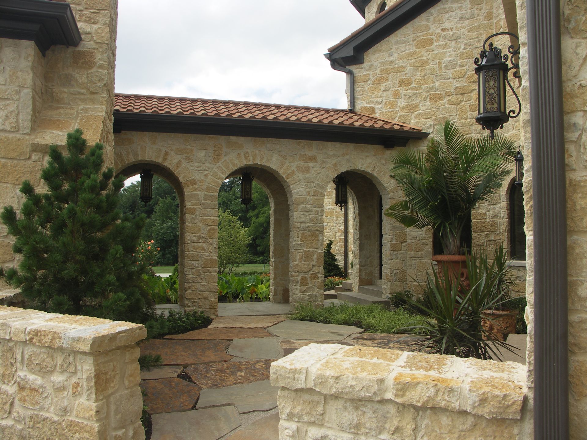 A Stone Mediterranean Building With Arches And A Lantern On The Side - Carmel, IN - Goldberg Design Group