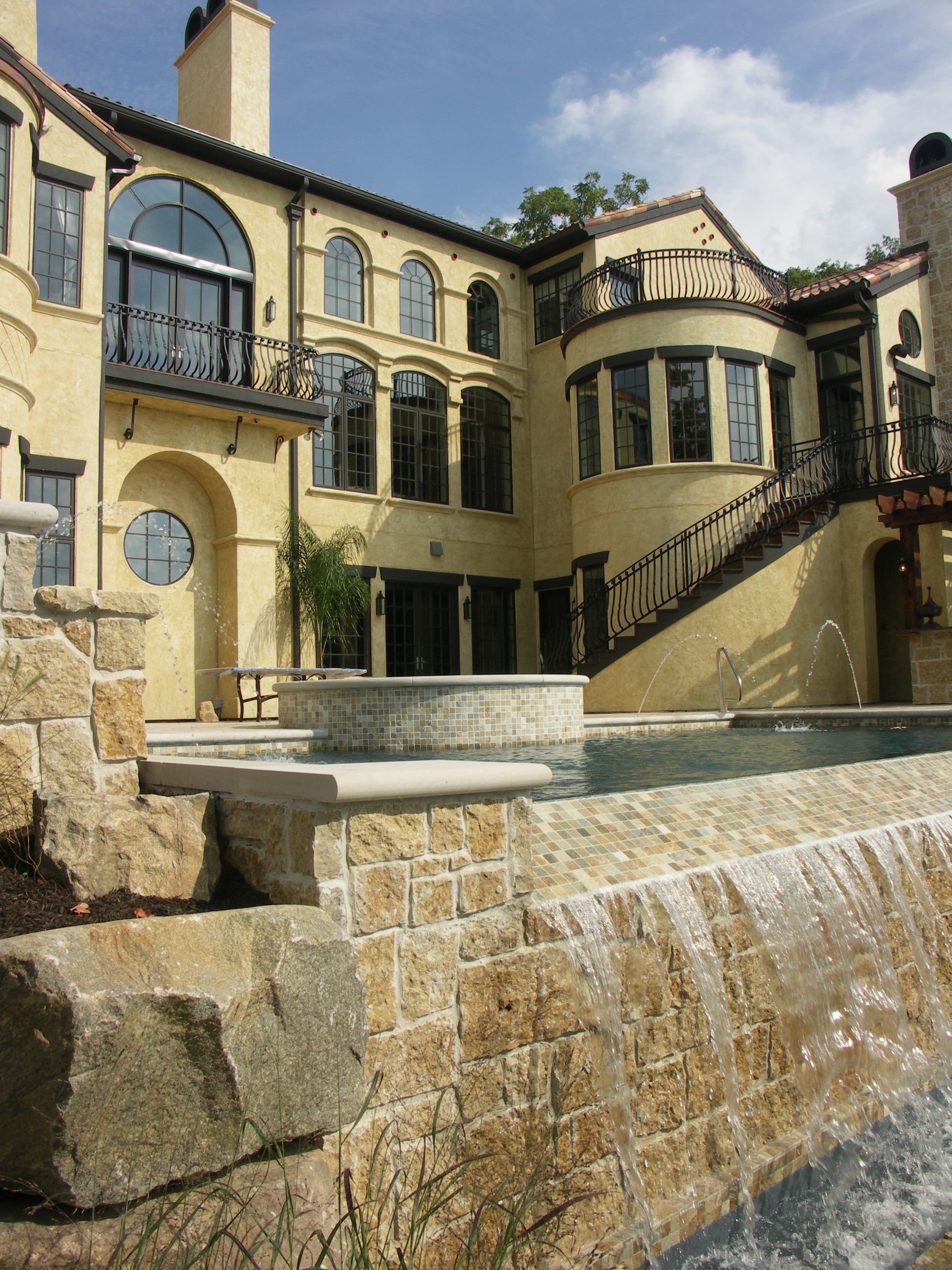 A Large Mediterranean House With A Swimming Pool In Front Of It - Carmel, IN - Goldberg Design Group