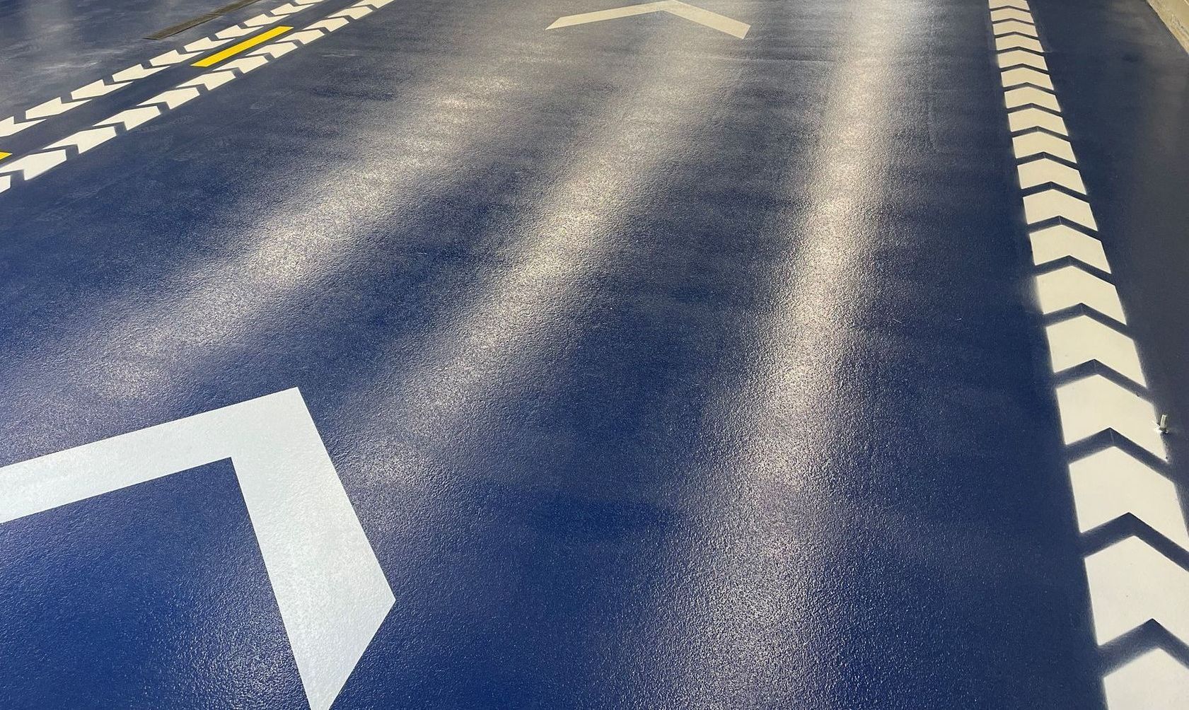 A close up of a blue road with white arrows on it