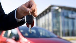 Man holding car keys, red car in background | Eagle Transmission & Auto Repair - Austin-North