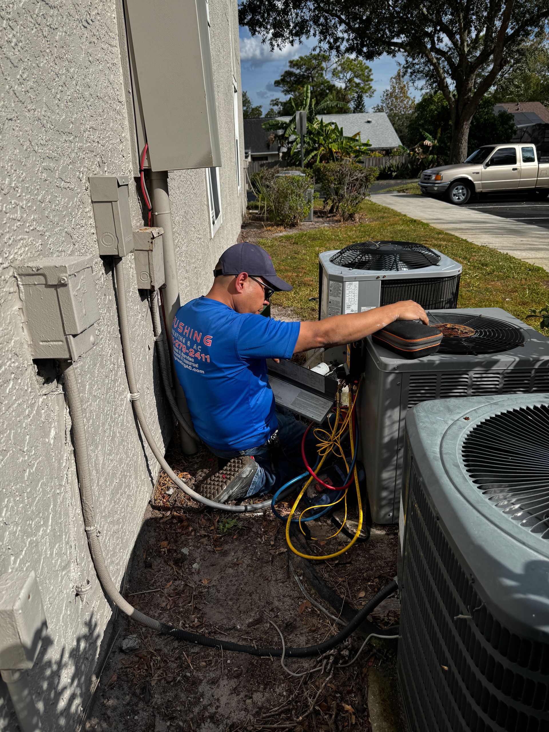 HVAC technician working on an air conditioning unit outside a building.