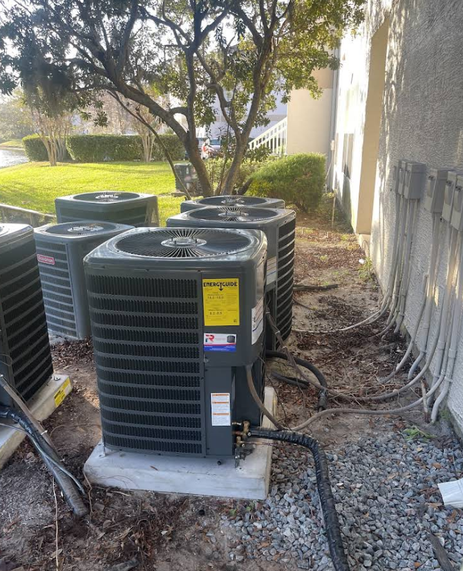 Several air conditioning units installed outside a building on concrete pads.