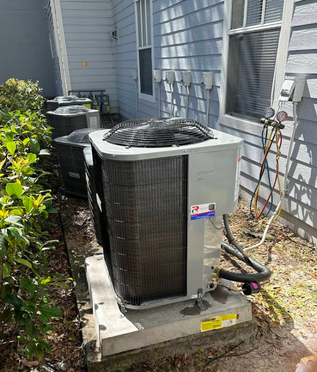Several air conditioning units installed outside a building on concrete pads.