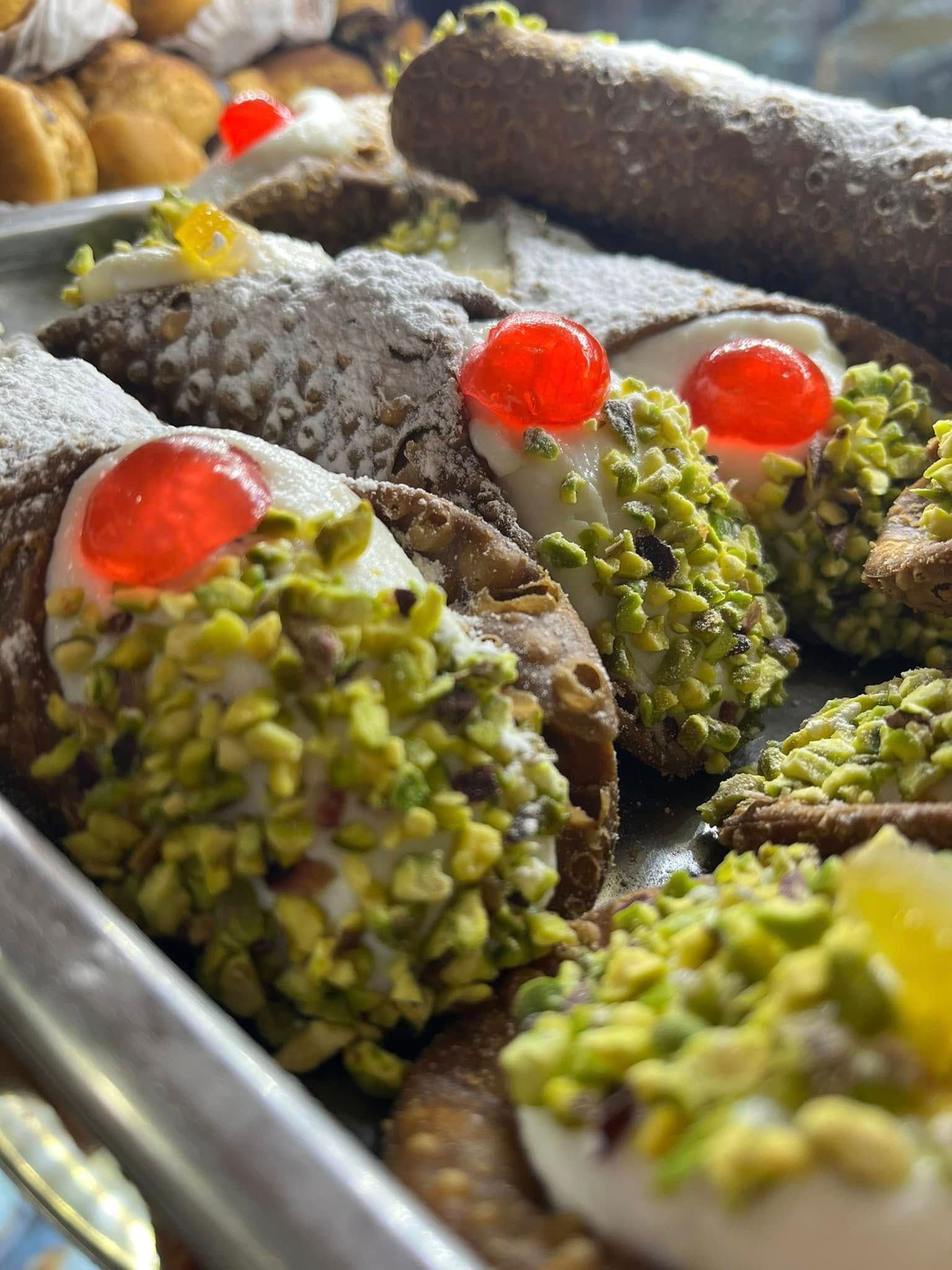 Vassoio di pasticcini al cioccolato assortiti, guarniti con pistacchi e ciliegie candite rosso vivo.