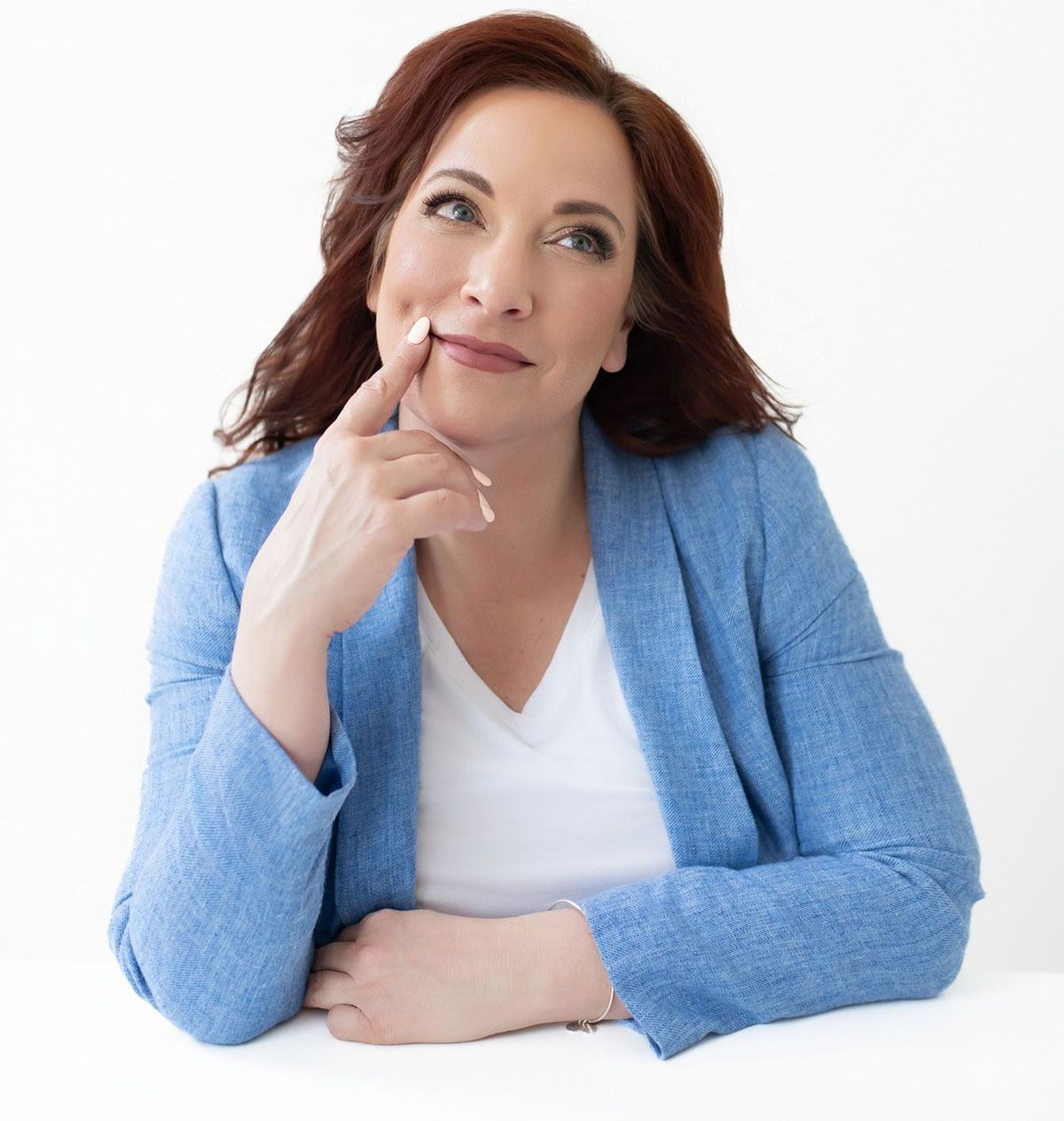 A woman in a blue jacket and white shirt is thinking