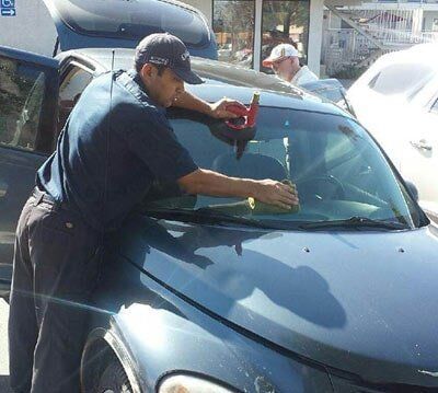 A man is cleaning the windshield of a car