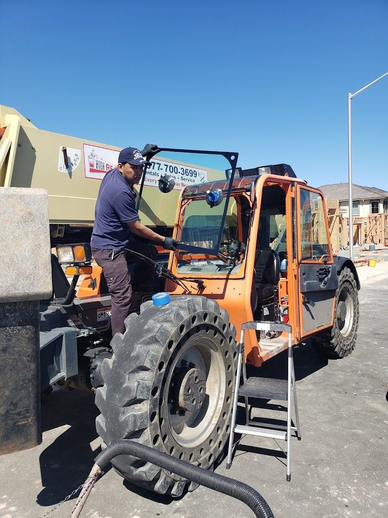 A man is working on a forklift in a parking lot.