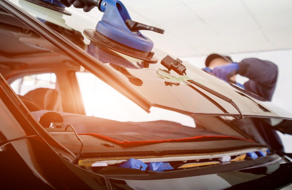 A man is installing a windshield on a car.