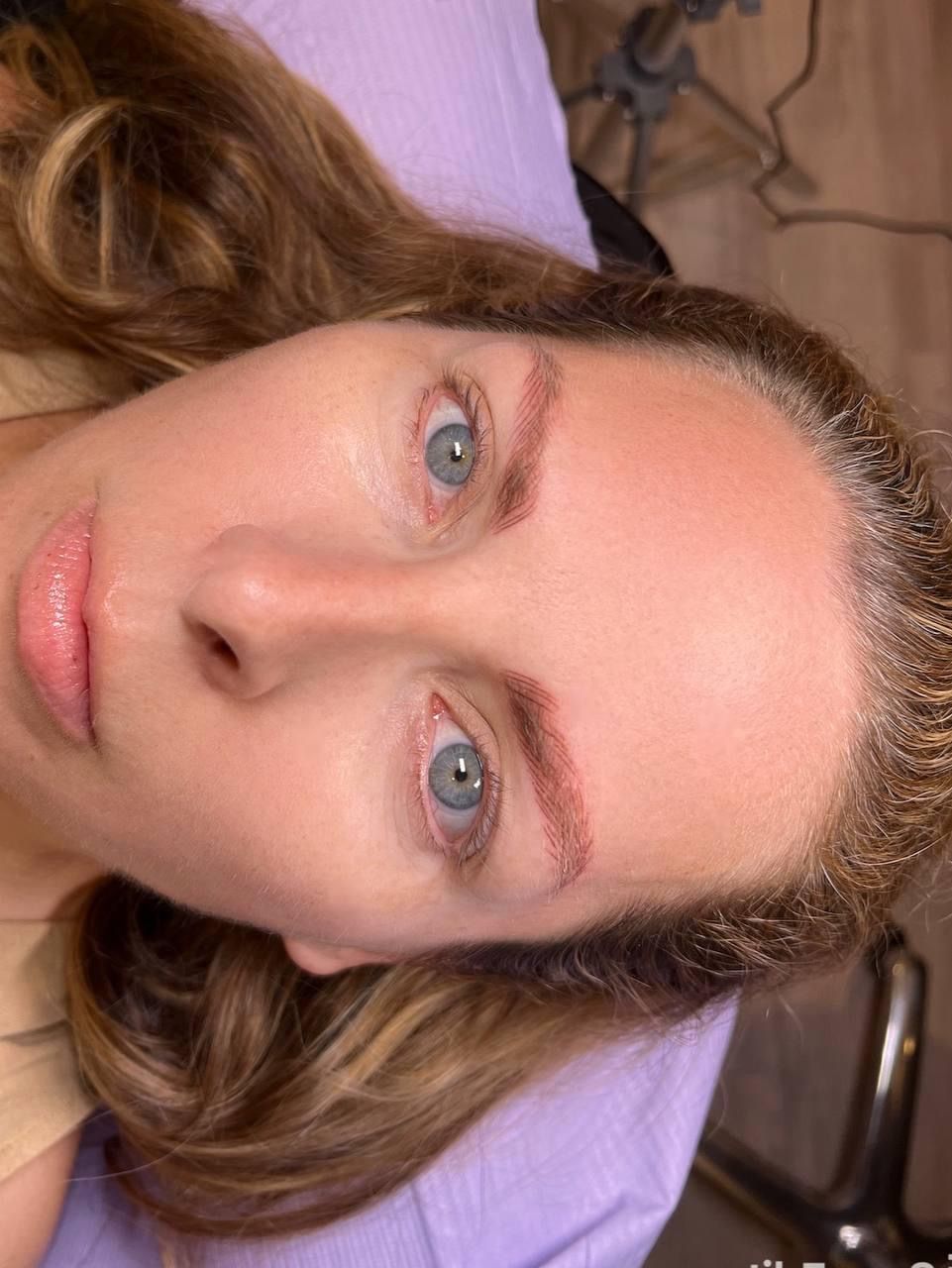 A woman with blue eyes is laying on a purple blanket.