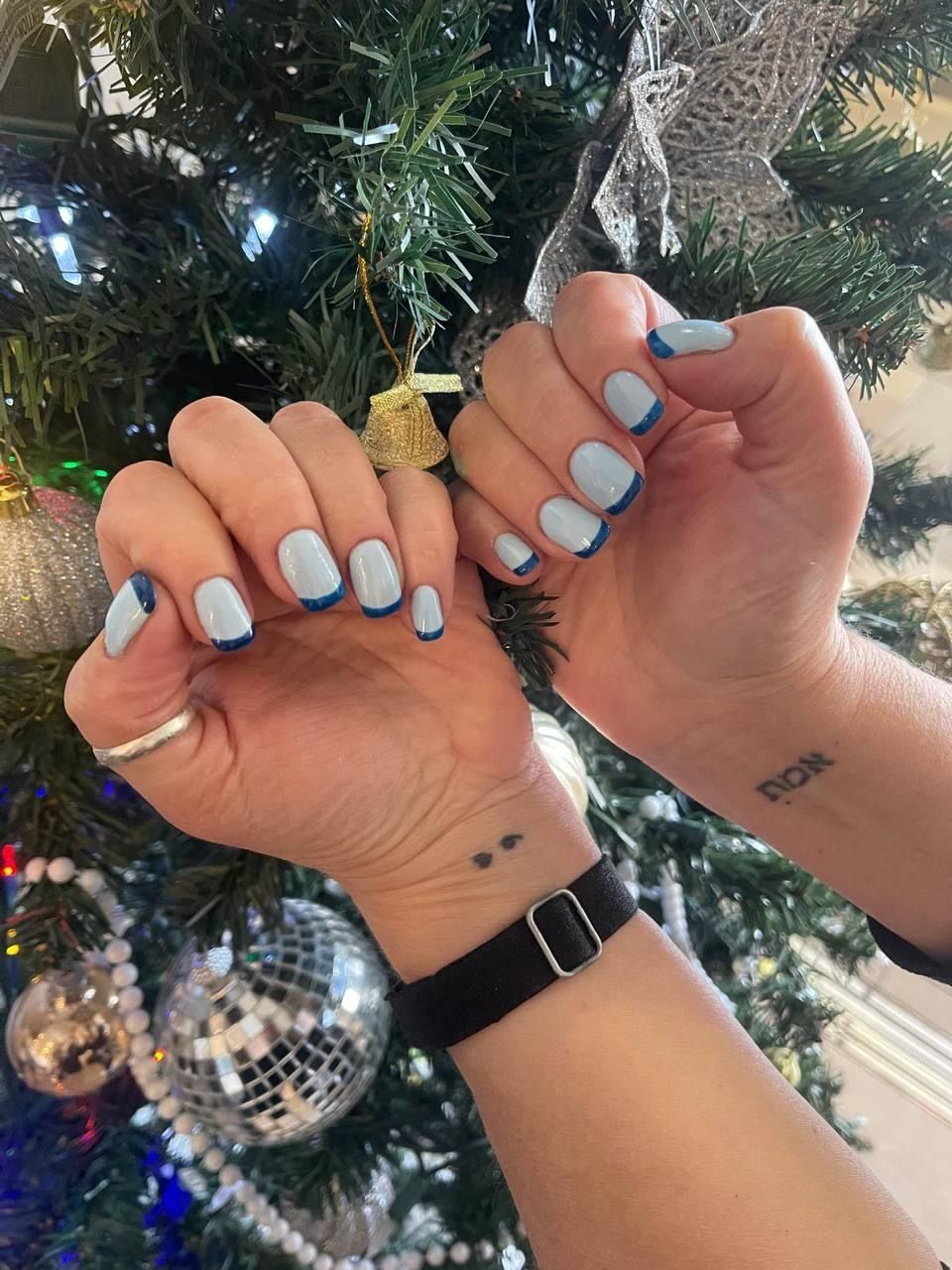 A close up of a person 's nails in front of a christmas tree.