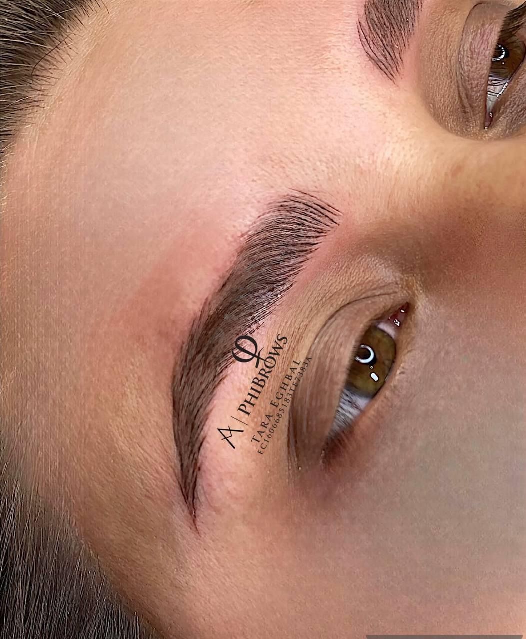 Close-up of a brow after microblading, brown ink, skin, with salon logo.