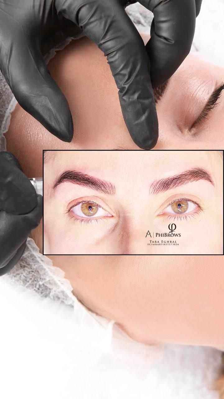 Hands in black gloves examining a woman's eyebrows after a cosmetic procedure.