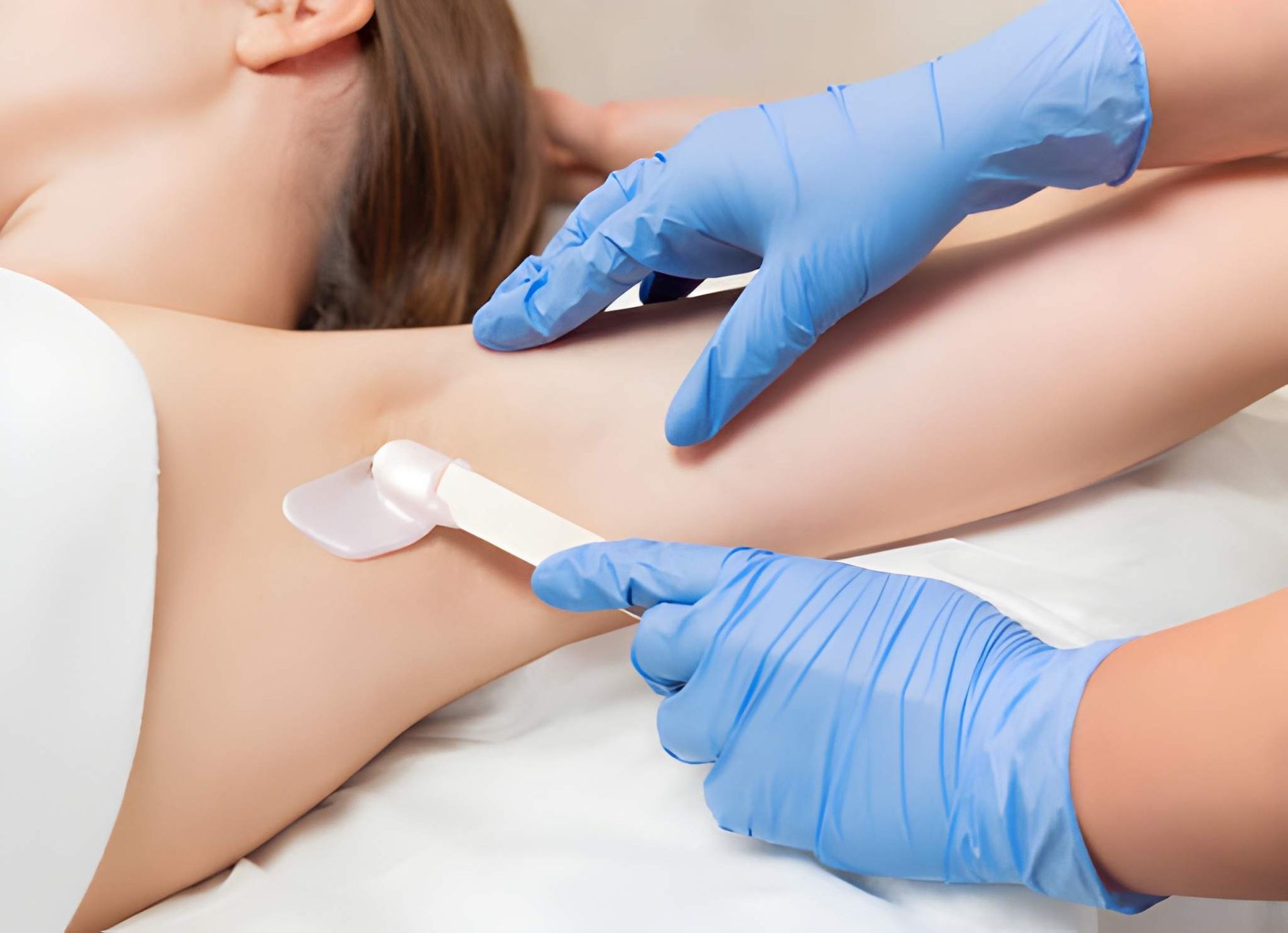 Hand with oval-shaped nails painted in a soft pink hue, extended against a matching pink background.