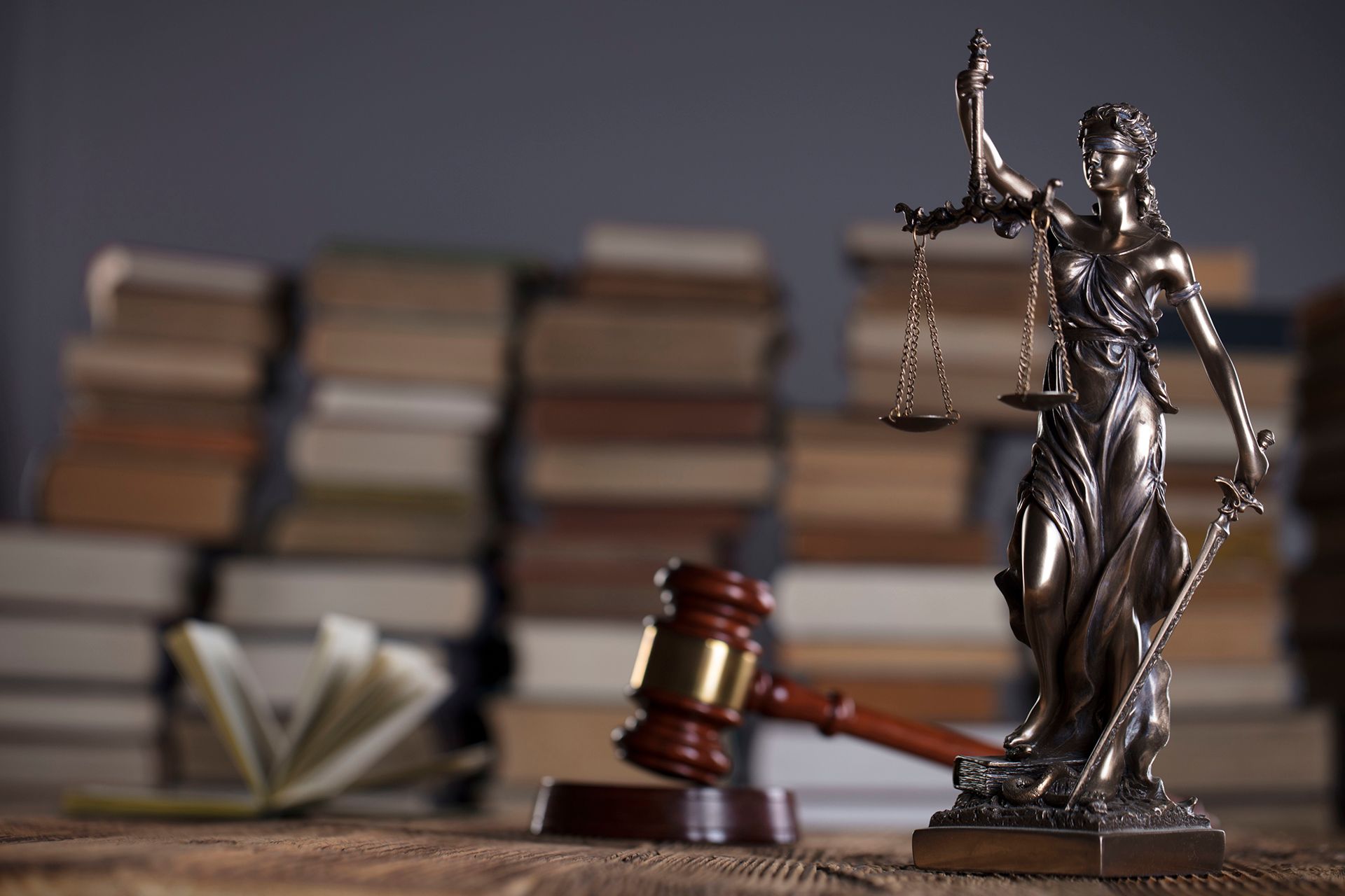 Una estatua de la justicia está sentada en una mesa de madera al lado de un mazo de madera.