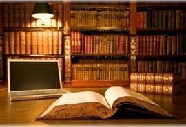 Hay un libro abierto sobre un escritorio al lado de una computadora portátil.