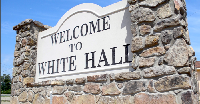 A stone wall with a sign that says welcome to white hall, AR
