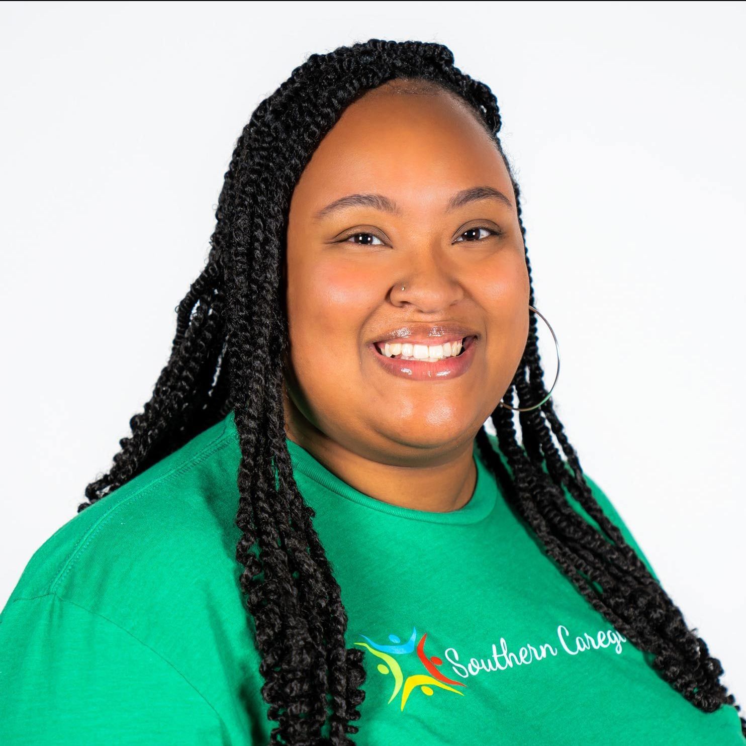 A woman with braids is wearing a green shirt that says southern caregivers