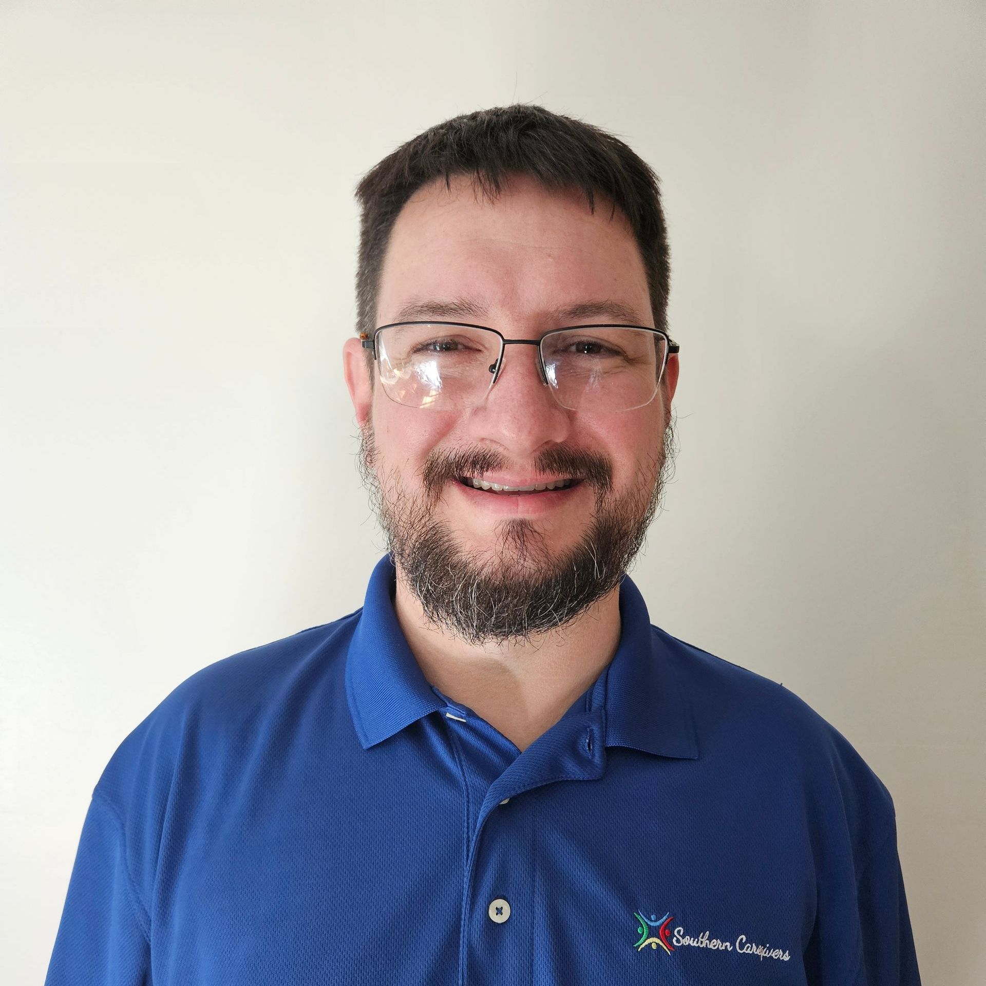 A man with glasses and a beard is wearing a blue shirt that says Southern Caregivers.
