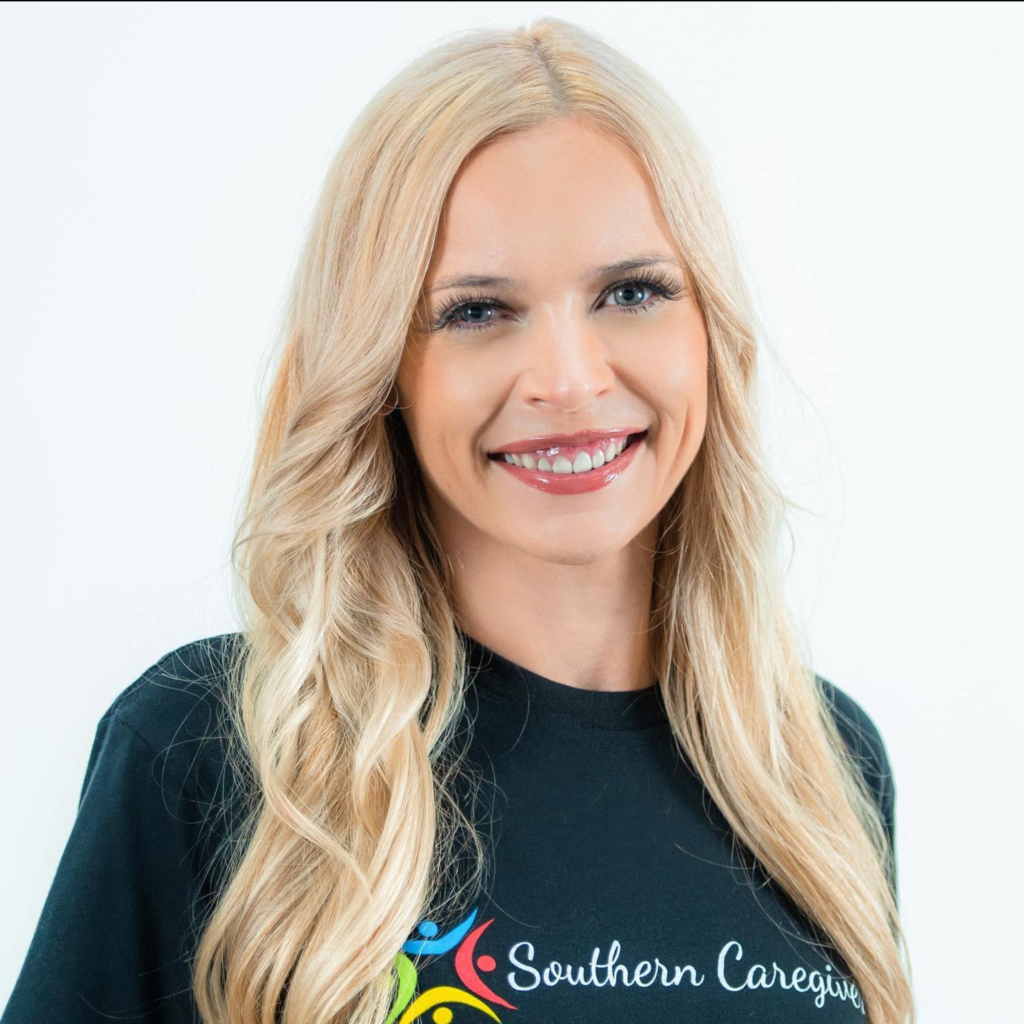 A woman wearing a southern caregiver shirt smiles for the camera. caregiver in northwest ar