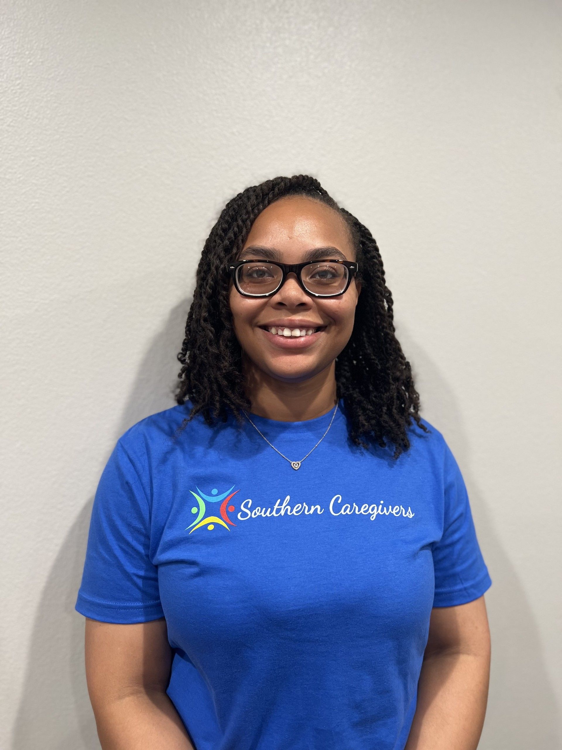 A woman wearing glasses and a blue shirt that says southern caregivers