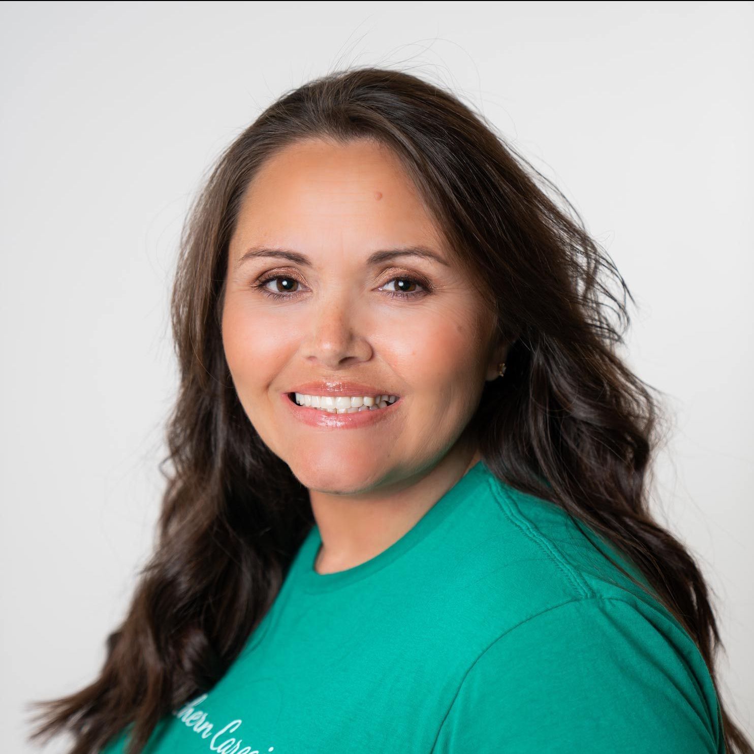 A woman in a green shirt is smiling for the camera