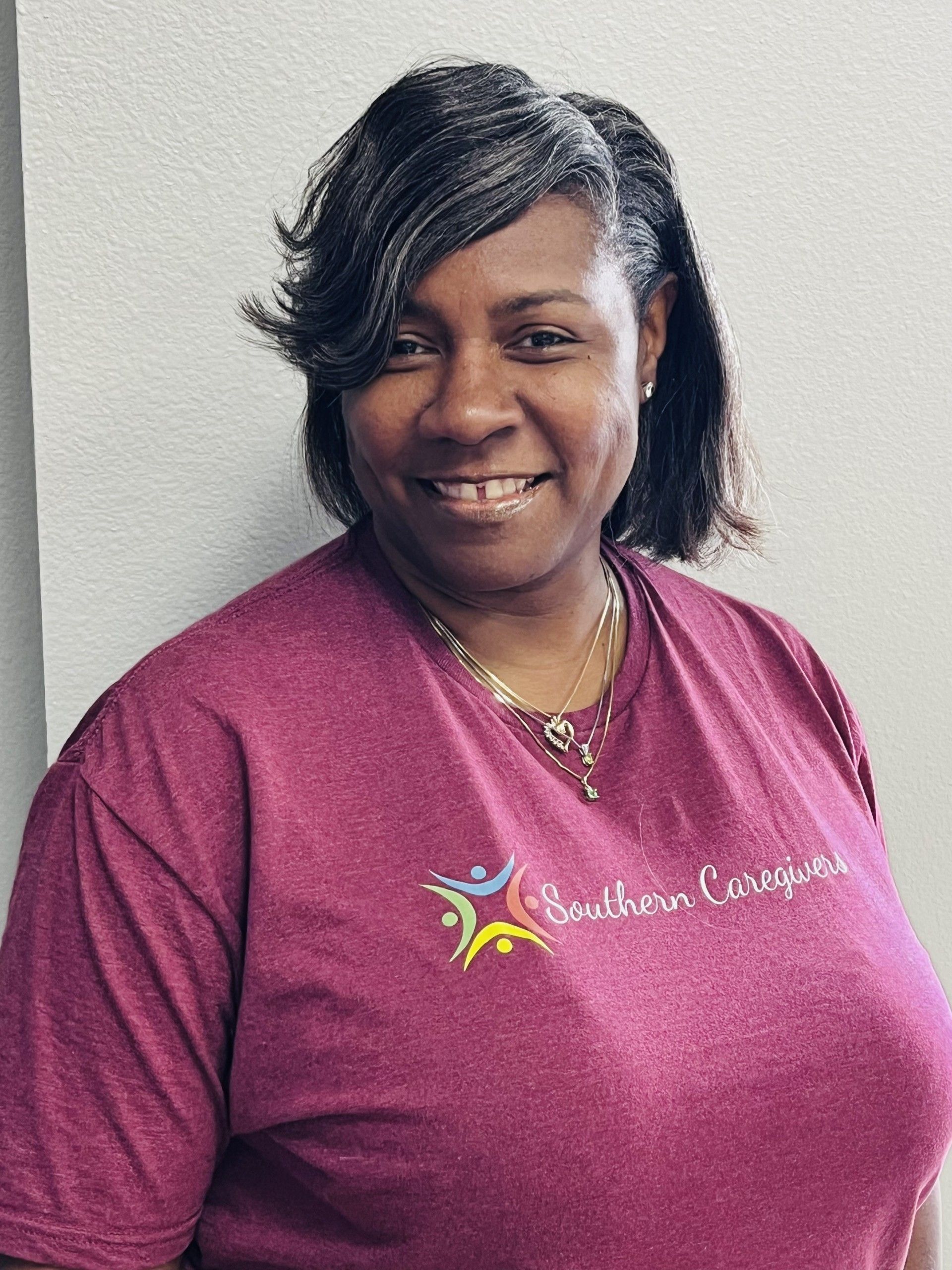 A woman wearing a purple southern caregivers t-shirt is smiling for the camera.