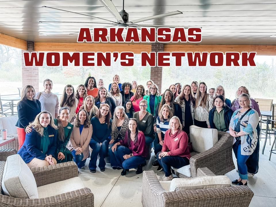 A group of women are posing for a picture with the words arkansas women 's network above them