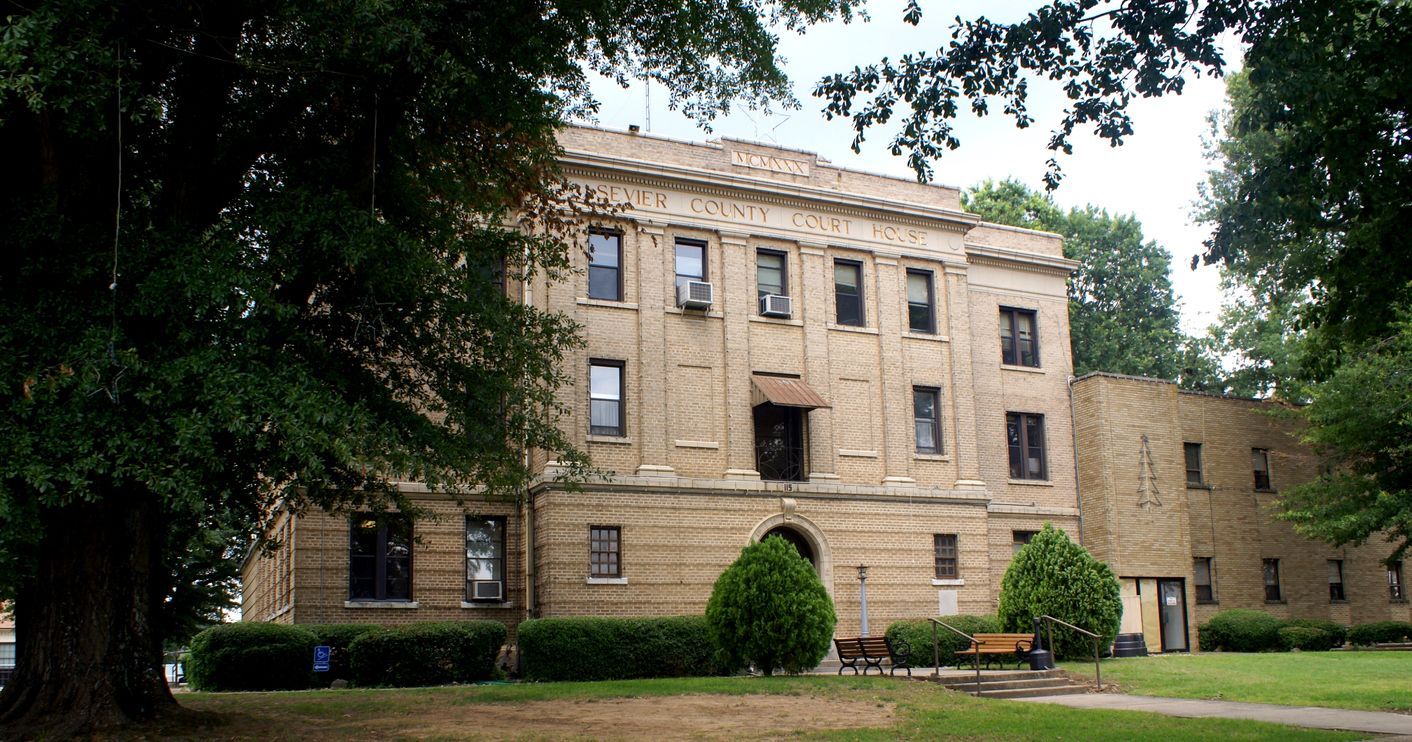 A large building with a lot of windows is surrounded by trees. Southern Caregivers building in De Queen, AR.