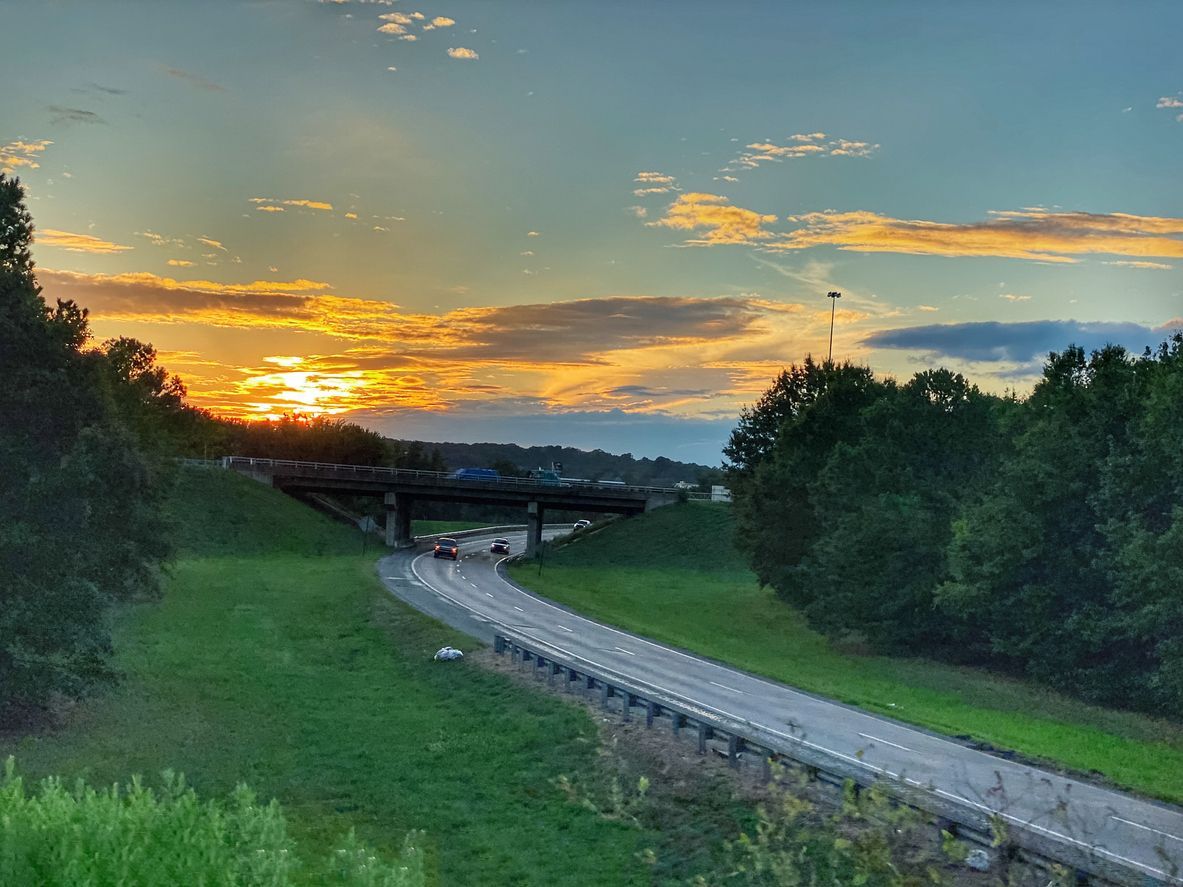 A sunset over a highway with a bridge in the background. Conway, AR. Caregivers in Conway. Southern Caregivers Conway.