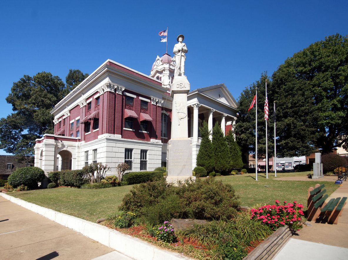 A large red and white building with a statue in front of it. Southern Caregivers building in Searcy, AR.