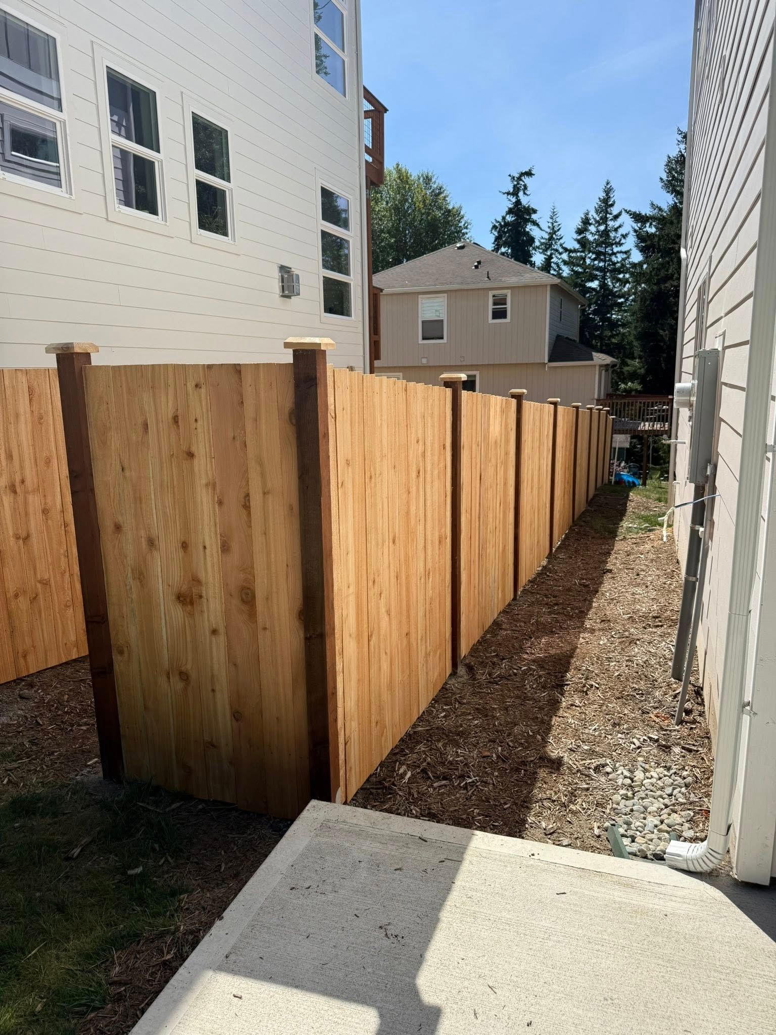 Wooden fence between buildings, with a dirt path alongside it.