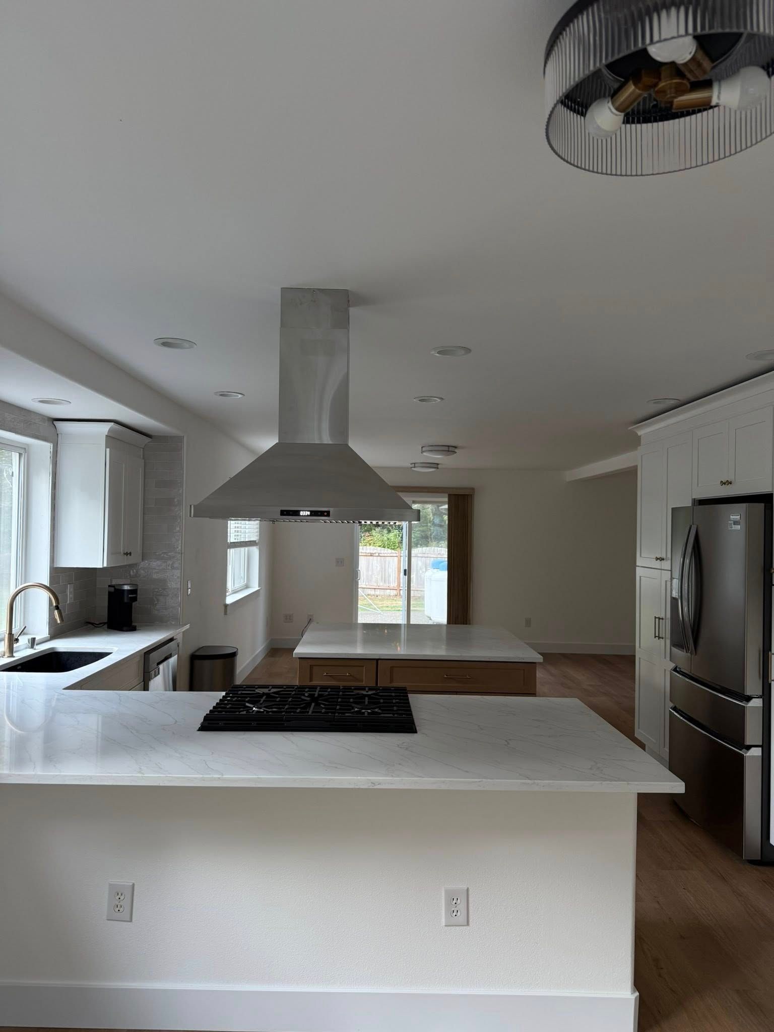 Modern kitchen with white countertops, stainless steel range hood, and two islands.